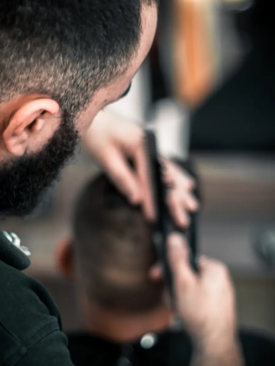 Alat cukur listrik sedang merapikan rambut di sekitar telinga